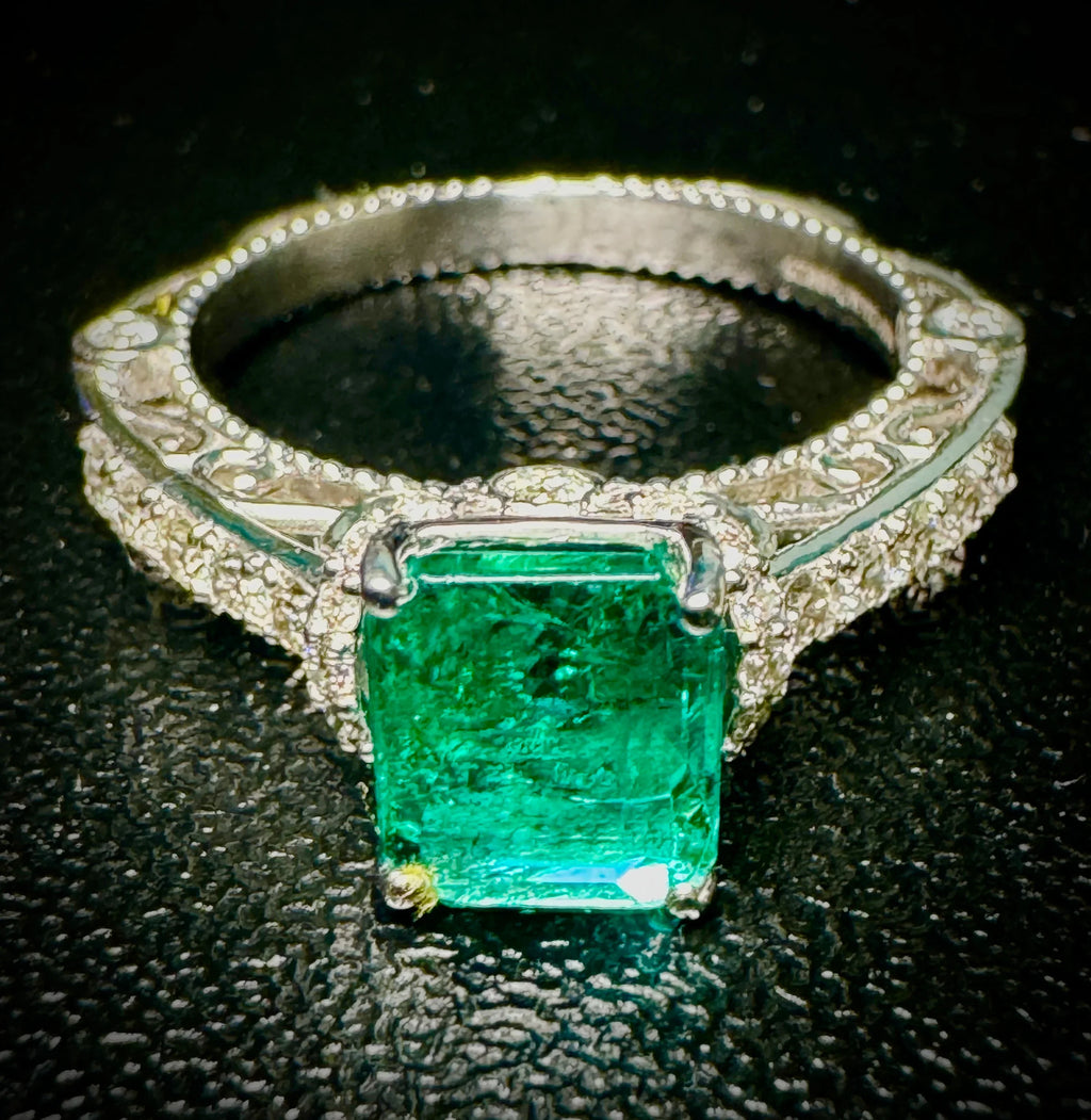 Platinum  ring with a green gemstone on a black background